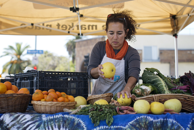 Rosario Mireles staffs the produce stands run by Community Services Unlimited, a non-profit in South Los Angeles. | Photo by Maya Sugarman for KPCC