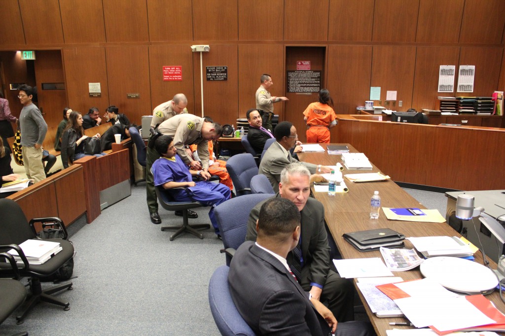 Alejandra Guerrero, in orange, is escorted out of the courtroom during a recess. Bailiffs prepare Alberto Ochoa, also in orange, along with Jonathan DelCarmen, in blue, to follow. | Daina Beth Solomon