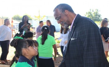 Council member Curren Price speaks with a student at West Vernon Elementary School at the launch of their grant bid.